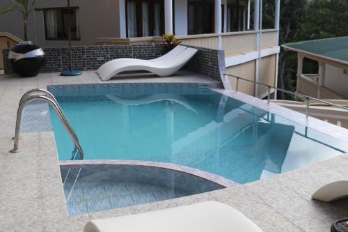a swimming pool with a bench next to a building at Mountain View Hotel in La Digue