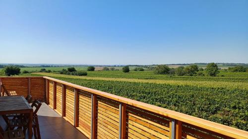 a wooden deck with a table and a view of a field at Vinařství U sv. Kříže in Prušánky