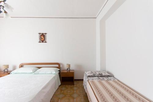 a white bedroom with a bed and a bench in it at Appartamento tra mare e montagna in Gaggi