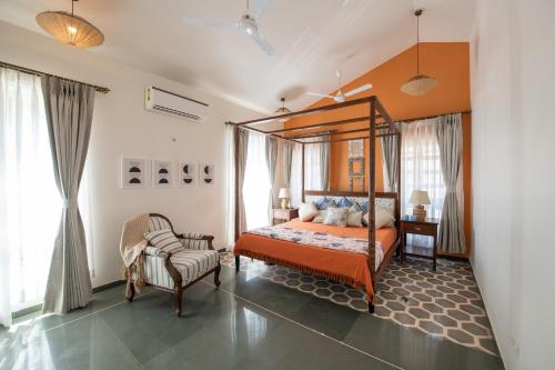a bedroom with a canopy bed and a chair at LohonoStays Colina Villa B in Vagator
