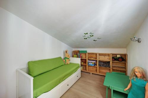 a little girl in a room with a green bed at Mansarda Albero Verde con Piscina in Casanova Lerrore
