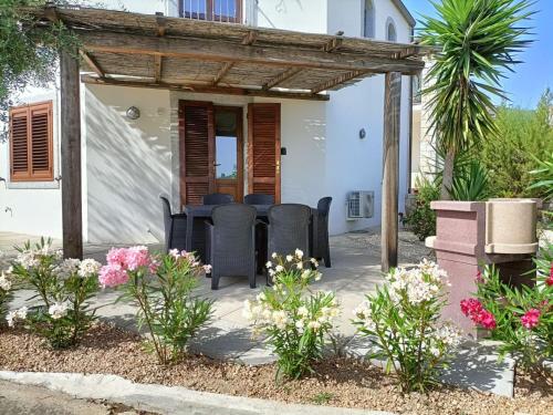 a patio with chairs and flowers in front of a house at Villa Vigna in Badesi