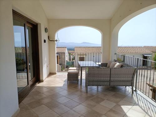 a patio with a couch and chairs on a balcony at Villa Vigna in Badesi