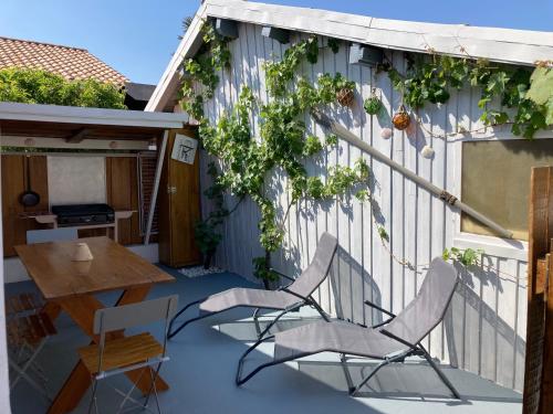 a patio with two chairs and a table and a building at Chalet in Le Teich