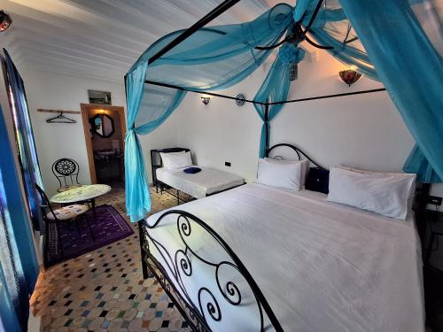 - une chambre avec un grand lit à baldaquin bleu dans l'établissement Riad Fes EL KAID, à Fès
