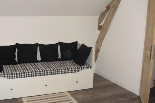 a couch with black pillows on a white wall at Gite de charme à Frémainville dans le vexin in Frémainville