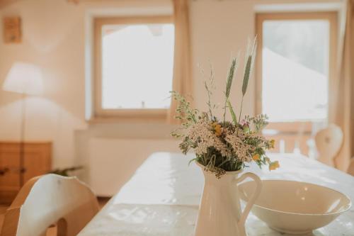 a white vase with flowers in it on a table at Gogererhof App Maria in Racines