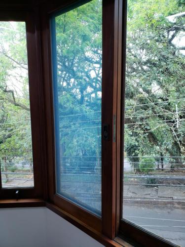 a window with a view of a tree at Pousada Monte Sião in Sao Paulo