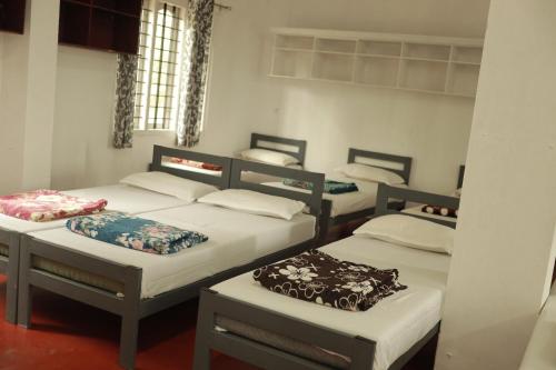 een kamer met drie bedden en een kamer met bij ASHRAMAM HEALTH RESORT in Kattappana