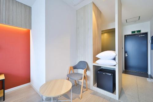 a small room with a table and a chair and a bed at Browndot Signature Hotel in Changwon