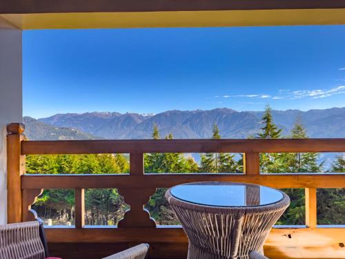 a table and chairs on a balcony with a view of mountains at TIMILO BOUTIQUE HOTEL in Tawang