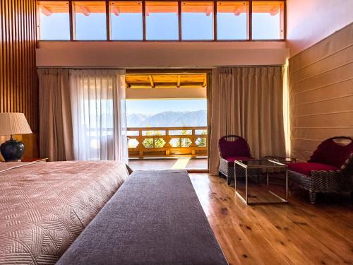 a bedroom with a bed and a view of a balcony at TIMILO BOUTIQUE HOTEL in Tawang