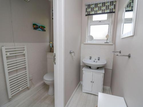 La salle de bains est pourvue d'un lavabo, de toilettes et d'une fenêtre. dans l'établissement Y Bwthyn Bach, à Lampeter