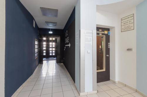 a hallway with blue walls and a white tile floor at zzzpace Smart-Hotel Bielefeld Zentrum in Bielefeld