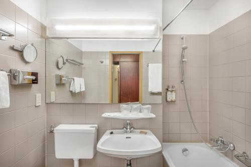 ein Badezimmer mit einem Waschbecken, einem WC und einem Spiegel in der Unterkunft Danubius Hotel Hungaria City Center in Budapest