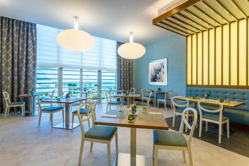 Hilton Garden Inn Tanger City Centre في طنجة: مطعم بطاولات وكراسي ونوافذ