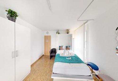 biały pokój z łóżkiem i krzesłem w obiekcie Über den Dächer von Chur (Montalin) w mieście Chur