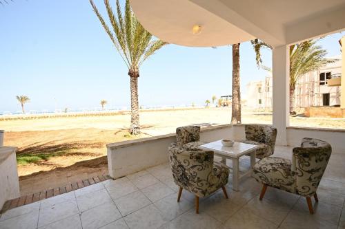 a patio with a table and chairs and a view of the beach at Beach house First Row sea view at Santa Monica next to Almaza Bay in Marsa Matruh