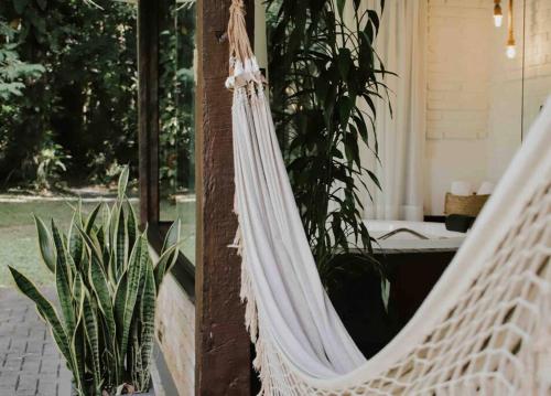 a white hammock hanging from a pole with plants at Casa de campo em Joinville com Hidromassagem e Lareira in Joinville