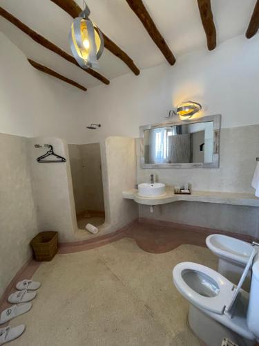 a bathroom with two toilets and a sink and a mirror at Mawe Zuri Resort in Watamu