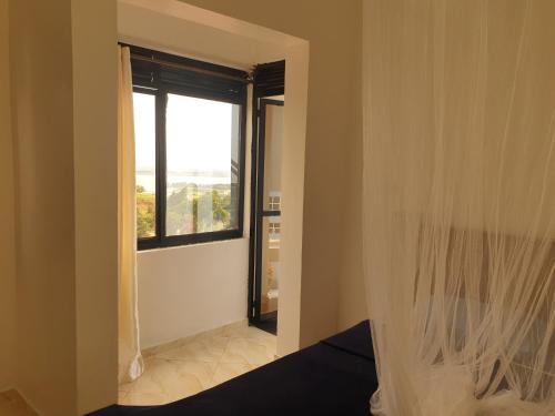 um quarto com uma janela e uma cama com uma cortina em Rosa Negra Uganda em Kigo