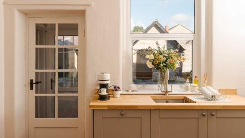una cocina con fregadero y una ventana con un jarrón de flores en South View, en Bakewell