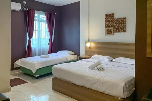ein Hotelzimmer mit 2 Betten und einem Fenster in der Unterkunft RedDoorz Syariah @ Jl D I Panjaitan Batu 7 Tanjung Pinang in Tanjung Pinang 
