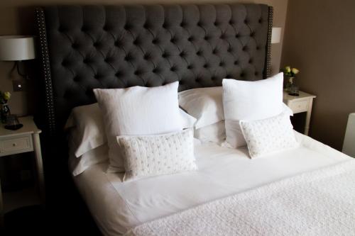 a white bed with white pillows and a gray headboard at The Fuzzy Duck in Newbold on Stour