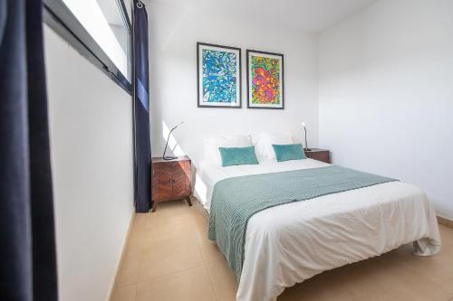 a bedroom with a white bed with blue pillows at Villa LanzaCosta Golf in Teguise