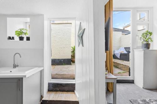 una cucina bianca con lavandino e finestra di The Cottage, Budleigh Salterton a Budleigh Salterton