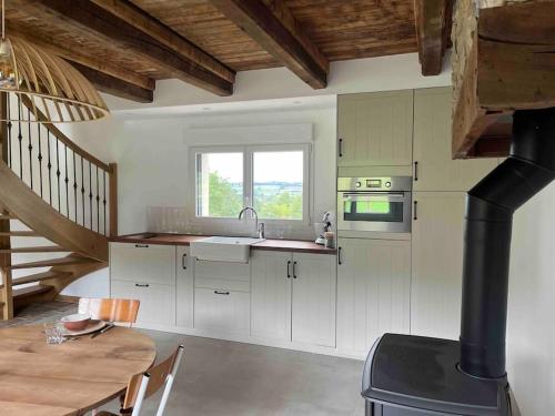eine Küche mit weißen Schränken und einem Herd mit Backofen in der Unterkunft Gite les bois d Orceil in La Gohannière