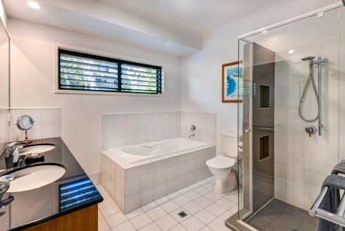 a bathroom with a tub and a sink and a shower at Casuarina Cove 14 & Buggy - Hamilton Island in Hamilton Island