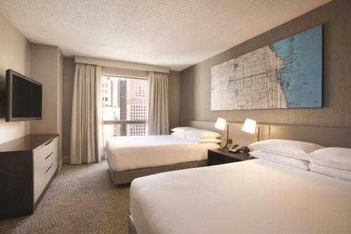 a hotel room with two beds and a television at Hilton Chicago Magnificent Mile Suites in Chicago