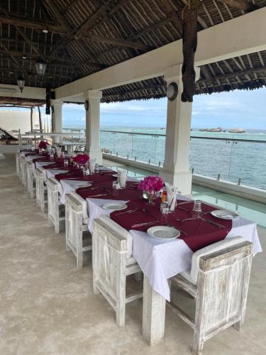 a row of tables on the beach with flowers on them at Mawe Zuri Resort in Watamu