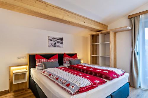 ein Schlafzimmer mit einem großen Bett mit roten Kissen in der Unterkunft Bergwelt A2 in Niederau