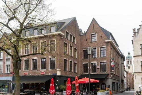 a large brick building with red umbrellas on a street at The View - spacious 2 bdr appt in with view in Antwerp