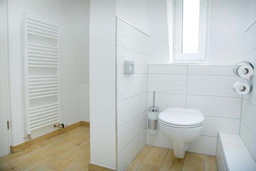 a white bathroom with a toilet and a window at Waldhotel Friedrichroda in Friedrichroda