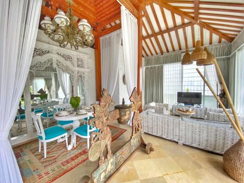 - un salon avec un lustre, une table et des chaises dans l'établissement Piramida's White Villa's Bali - Joglo, à Canggu