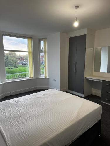 a bedroom with a large white bed and two windows at OYO Cheetham Hill Guest House in Manchester