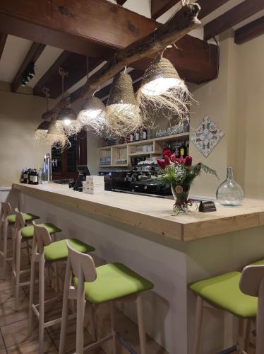 a kitchen with a bar with green stools at Hostal Loreto in Denia