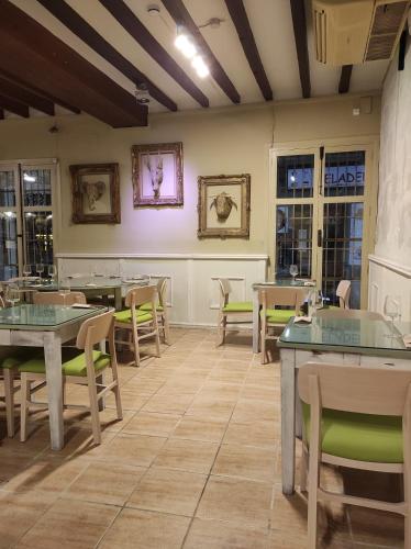 a dining room with tables and chairs and windows at Hostal Loreto in Denia