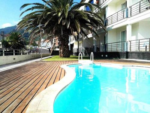 a swimming pool next to a building with a palm tree at Marina Mar Vila Franca do Campo in Vila Franca do Campo