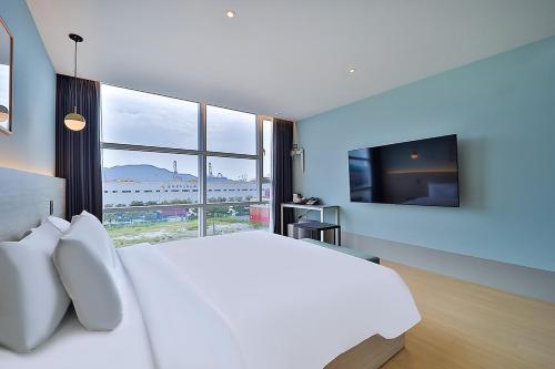 a bedroom with a large white bed and a large window at Browndot Signature Hotel in Changwon