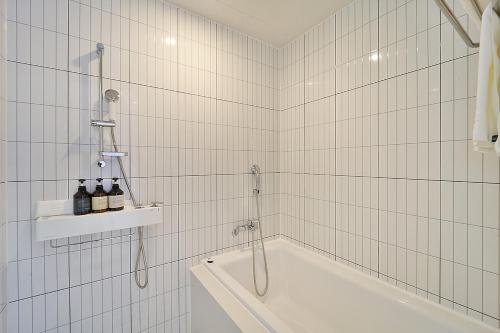a white tiled bathroom with a shower and a tub at Browndot Signature Hotel in Changwon