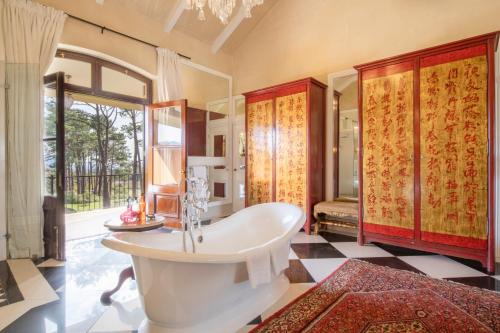 a bathroom with a tub and a large window at La Residence in Franschhoek