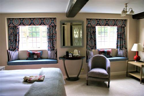 a bedroom with a bed and a chair and two windows at The Eastbury & Spa in Sherborne