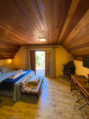1 dormitorio con cama y techo de madera en Pousada Sotaque Mineiro en Cunha