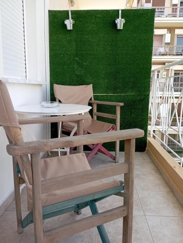 a table and chairs on a balcony with a green wall at Gk Suites-Constantin view , auto check-in 24h in Larisa