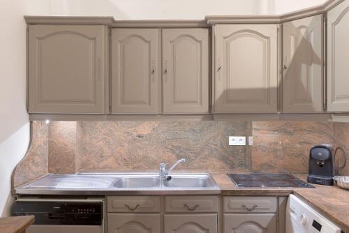 une cuisine avec des armoires blanches et un évier dans l'établissement Le Château Vallombrosa by Halldis, à Cannes