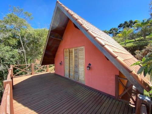 a small red house with a large wooden deck at Pousada Sotaque Mineiro in Cunha